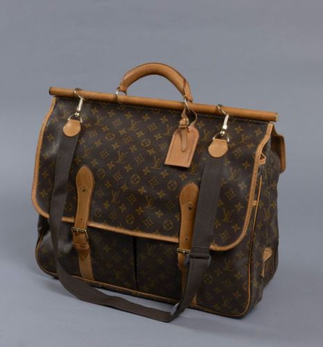 Louis VUITTON, Sac Chasse en toile monogram, étiquette à bagage et poignée en cuir naturel, bandoulière ajustable en toile. D'un côté, une boucle de fermeture donnant sur une grande poche et un compartiment zippé, de l'autre double boucles de fermeture do