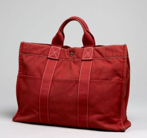 HERMES, Fourre-tout en toile rouge, multipoches à l'éxtérieur, deux anses portées main à la couleur. 30 x 42 cm. Très bon état.