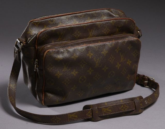 Louis VUITTON Nile en toile monogram avec anse bandoulière ajustable, poches avant et intérieures zippées. Petites usures. Patine d'usage