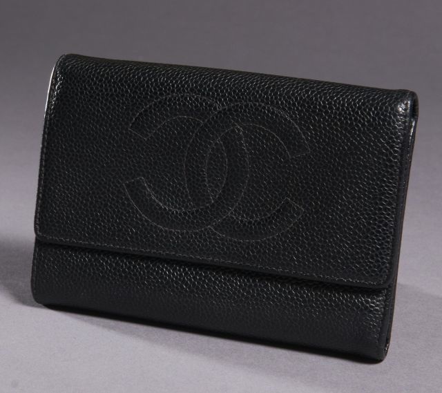 CHANEL Grand porte-feuille en cuir grené noir siglé sur le devant. Porte-billet et porte-cartes, une pochet extérieure zippée. Légère patine d'usage. Bon état.