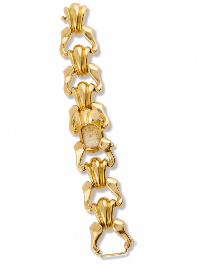 PATEK PHILIPPE REF. 2100. BY SERPICO Y LAINO Very fine and unusual, oval 18K yellow-gold lady's wristwatch with concealed dial, inserted in a wide and heavy 18K yellow-gold bracelet, made of six shell-shaped elements linked together by scrolls retailed by