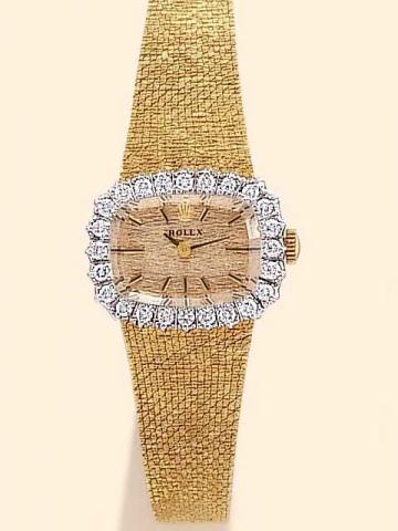 Rolex, Ref. 8335. Pro-duced in the 1970's.Fine, cushion-shaped, 14K yellow gold and diamonds lady's wristwatch with linen textured 14K yellow gold bracelet.