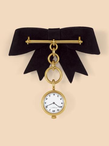 Les Imperiales.Patek Philippe, Geneve, No. 1607802, case.No. 2870521, Ref. 4761. Made in 1989..Fine, 18K yellow gold, lady's lapel quartz watch hanging from.an 18K yellow gold chain and brooch fastened to a suede.bow. Accompanied by a Patek Philippe box a