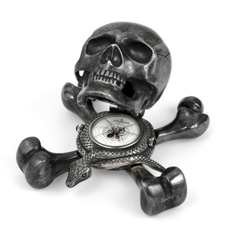 CORUM Jolly Roger No. 1.Corum, Jolly Roger, Ref. 677.993, No. 001. Made in a.limited edition, circa 2000..Silver quartz form clock in the shape of a skull atop a snake.and crossbones, with concealed dial and alarm..To be sold without reserve