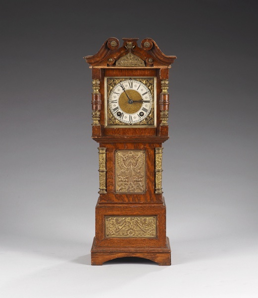 An amusing early 20th century German metal mounted oak mantel clock in the form of a longcase clock