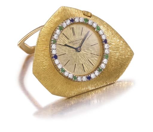 Patek Philippe. A fine and rare 18K gold, diamond, sapphire and emerald-set asymmetrical keyless lever travel watch, formerly the property of Dizzie Gillespie
