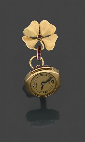 UTI. MONTRE DE REVERS. VERS 1940. en or jaune, surmontée d'un trêfle à quatre feuilles et argémentée de petits rubis calibrés.. Cadran et mouvement signés.. Travail français.. Poids brut: 8,5 gr.. A gold and rubis lapel watch by Uti.